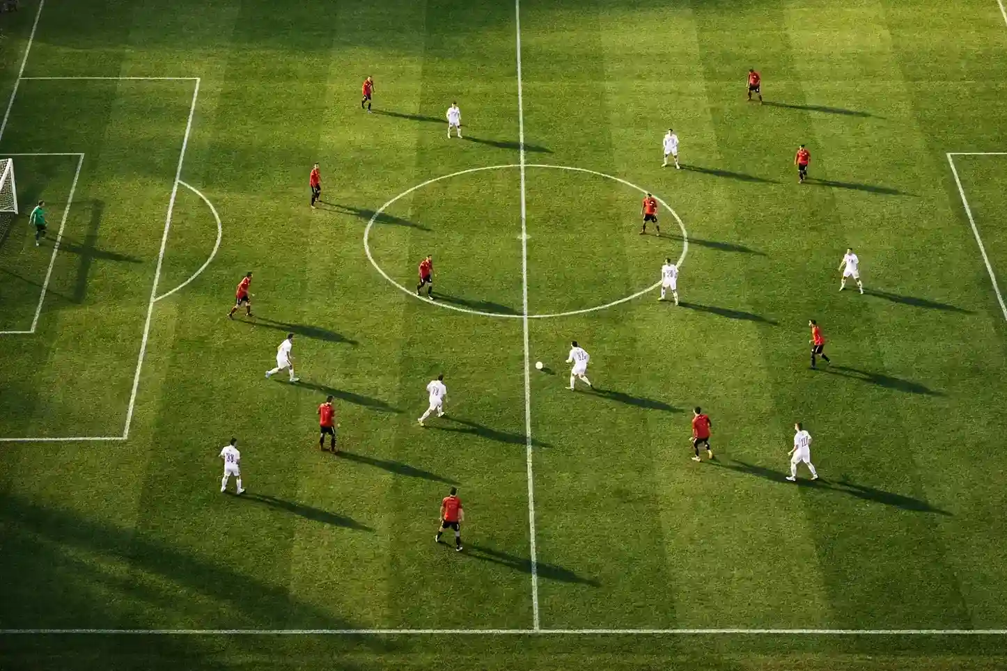 Voetbalveld van bovenaf met spelers in actie tijdens een wedstrijd